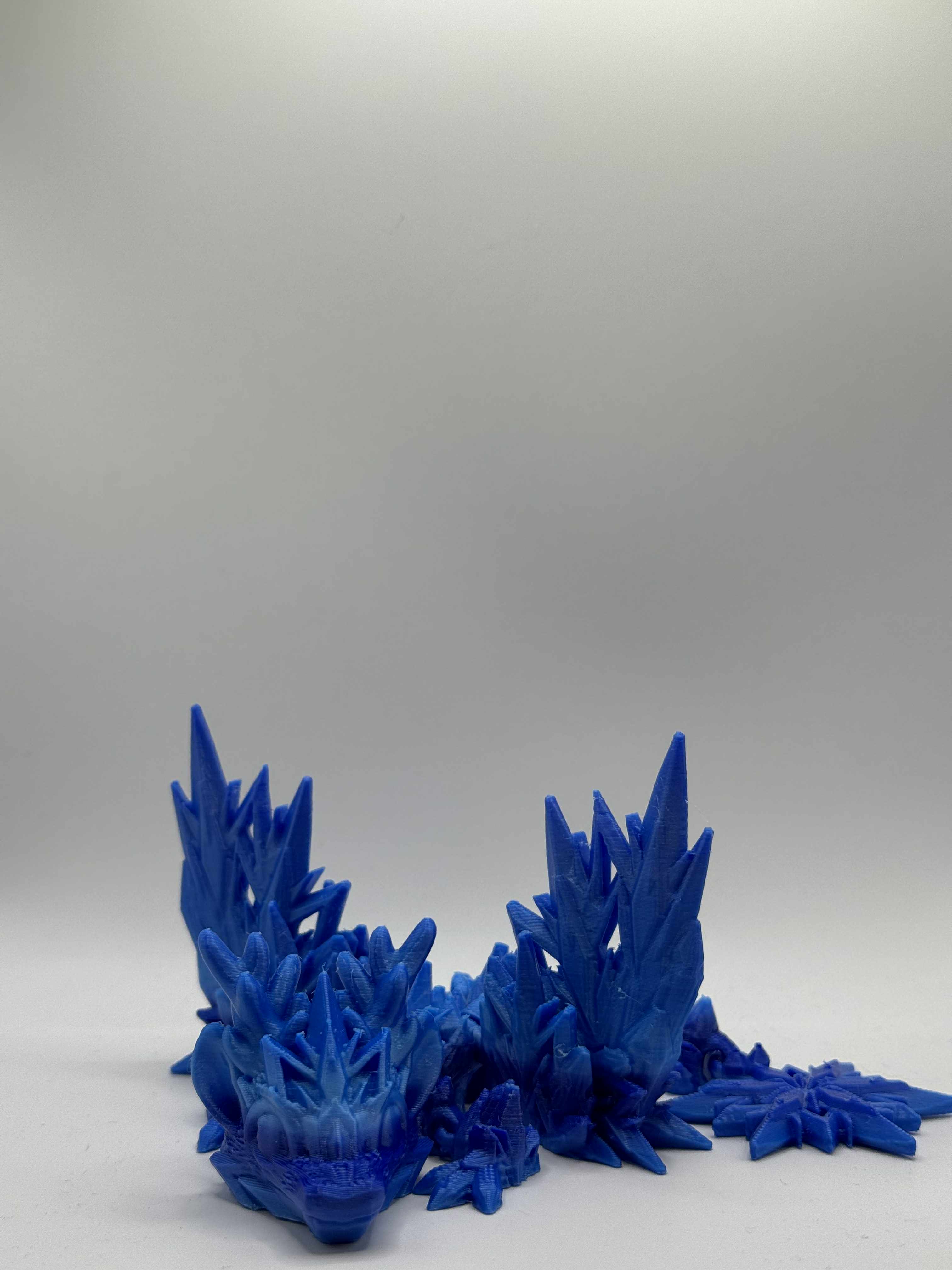 Lille isdrage i blå, marineblå og lyseblå med vinger