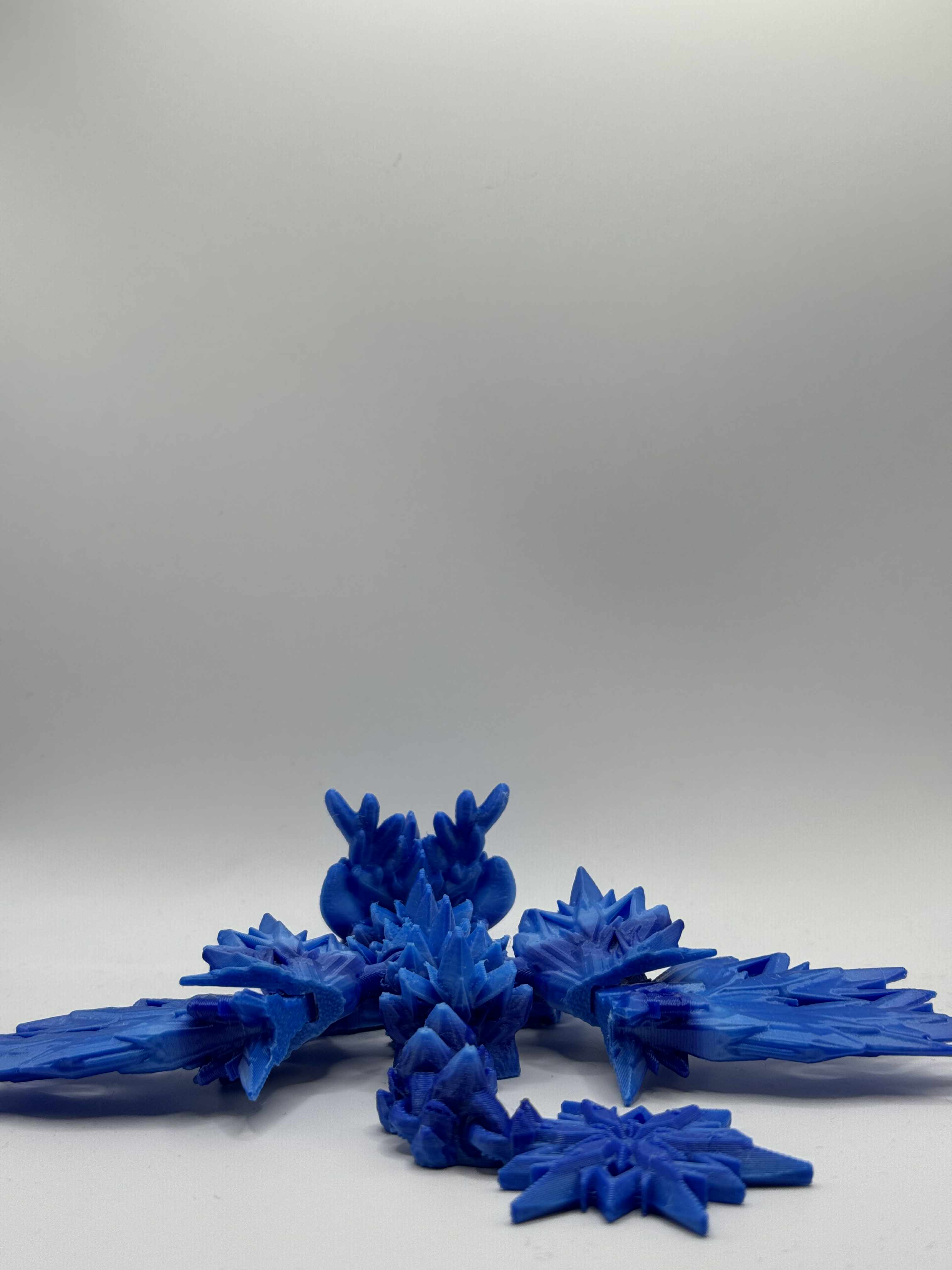 Lille isdrage i blå, marineblå og lyseblå med vinger